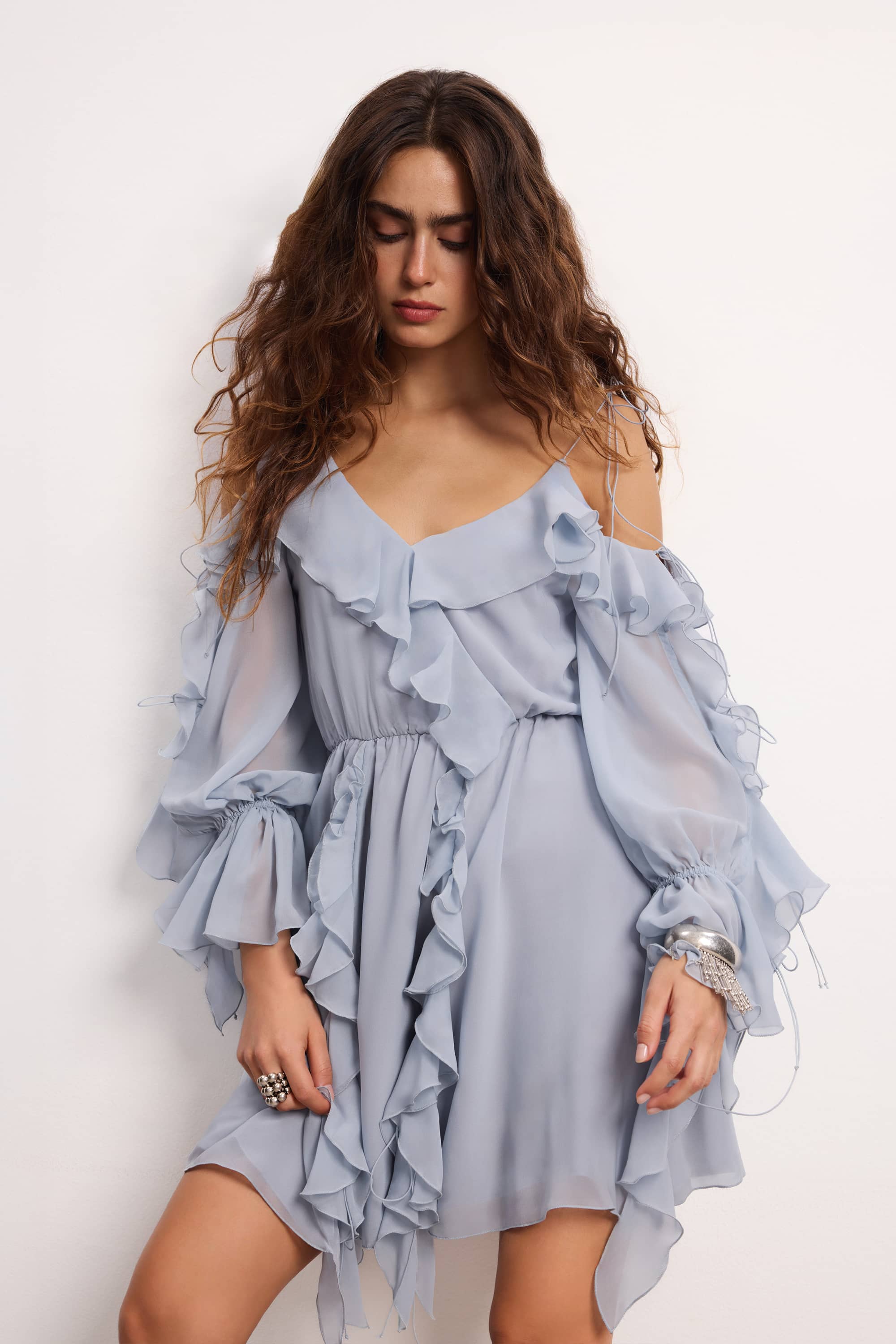 Woman wearing a blue fog off-shoulder ruffled Morning Forest mini dress on a white background, front view