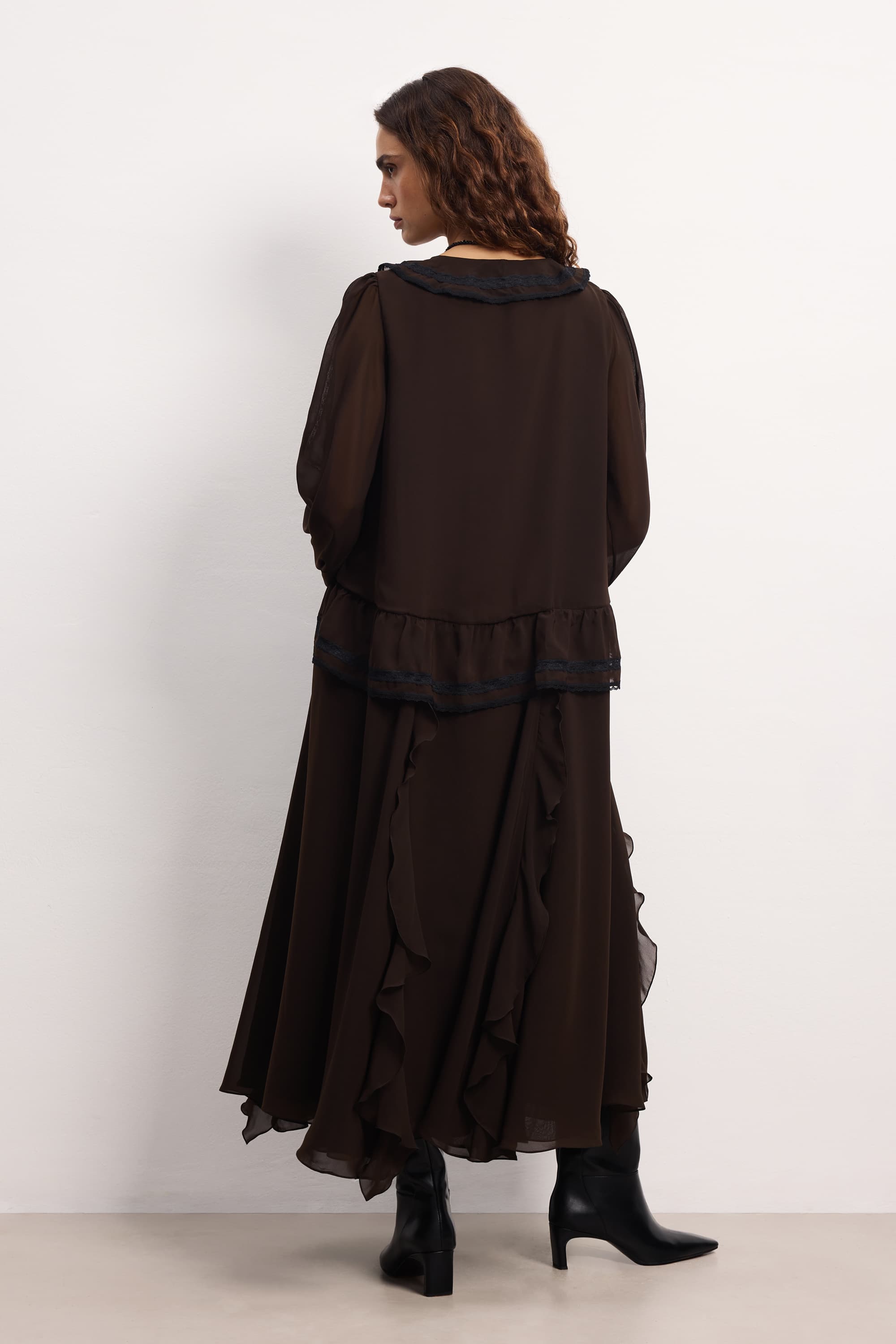 Woman wearing a dark brown layered outfit against a white background